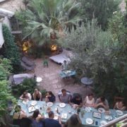 Une longe table dans le jardin avec des personnes qui mangent et discutent