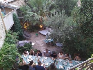 Une longe table dans le jardin avec des personnes qui mangent et discutent